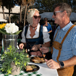 Two people standing up at table and eating a meal