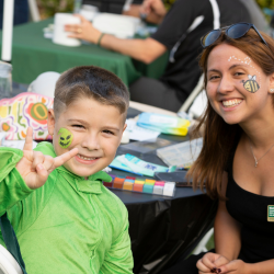 Woman and a young child smiling at camera while child makes USF Bulls hand gesture.