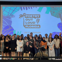 Group of students standing in front of projector that reads "Poetry Out Loud"