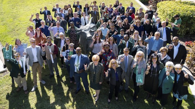 Faculty, staff, and community members gathered around the bull statue on campus