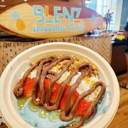 A bowl with strawberries, bananas, and covered with chocolate.