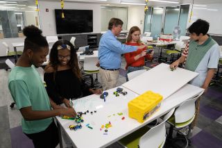 A group of students and a professor working with legos