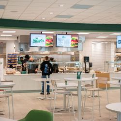 Well lit cateteria with a serving area and tables.