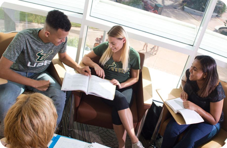 A group of students sitting in a circle of chairs reading textbooks