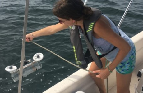 Student on a boat pulling a sample from the water