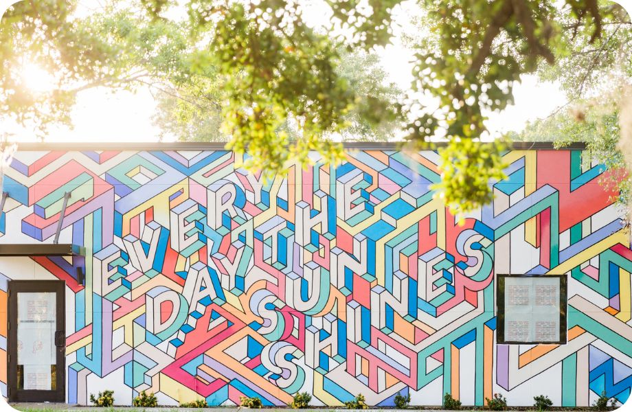 Colorful mural on the side of a building that reads "Every Day The Sun Shines"