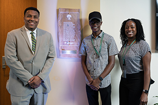 People standing in front of the land acknowledgment plaque