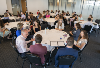 Students and business leaders sitting at round tables in a conference room