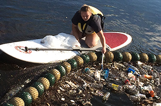 student in kayak collecting garbage from water goat