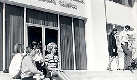 black and white photo of students sitting on the steps in front of a buliding