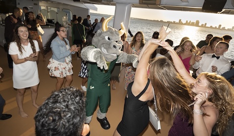 Rocky and students dancing during the cruise with the setting sun and city skyline in the background