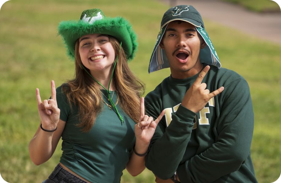 Two students wearing all green and all green hats