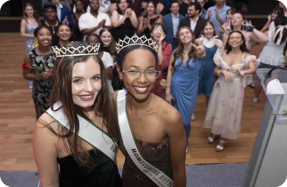 Two students wearing homecoming sashes and crowns