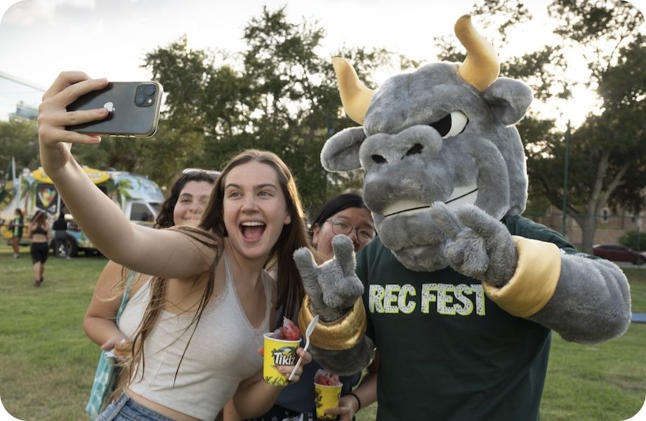 A student holding a camera and taking a selfie with Rocky