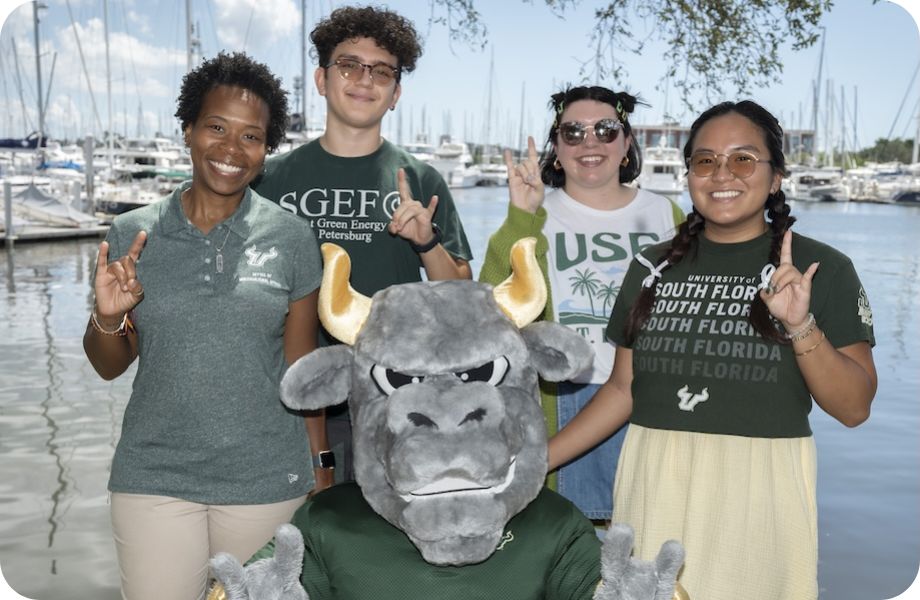 Four students surrounding Rocky the Bully and making bull signs with their hands