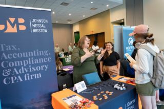 Student standing near table talking to people about potential jobs