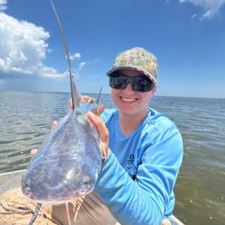 Woman holding a large silver fish and holding it towards camera. 