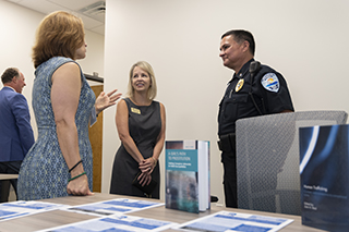 Two women talking to a police officer. In the foreground is a table with a book and pamphlets.