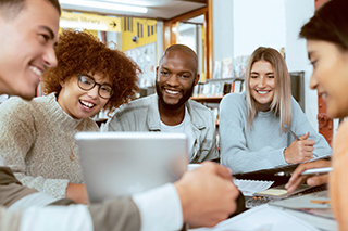 people sitting around smiling while looking at a laptop