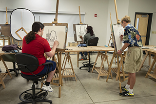students drawing at easels in a classroom