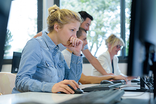 Students sitting at a table looking at their computer monitors