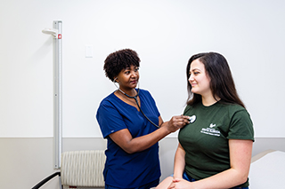 Nurse checking hearbeat on female patient.