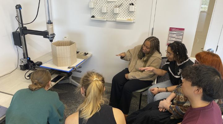 Group of students surrounding a 3D printer and it's creation