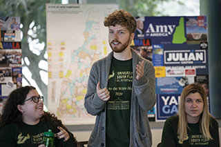 Student standing up talking with two students sitting on either side