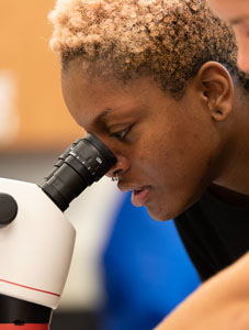 female student looking in microscope