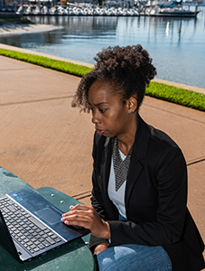 A student sitting outside looking at a laptop