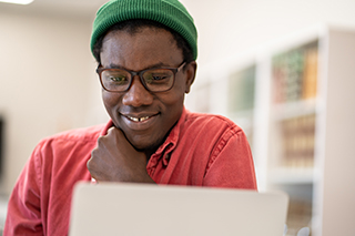 a man smiling while looking at a laptop screen