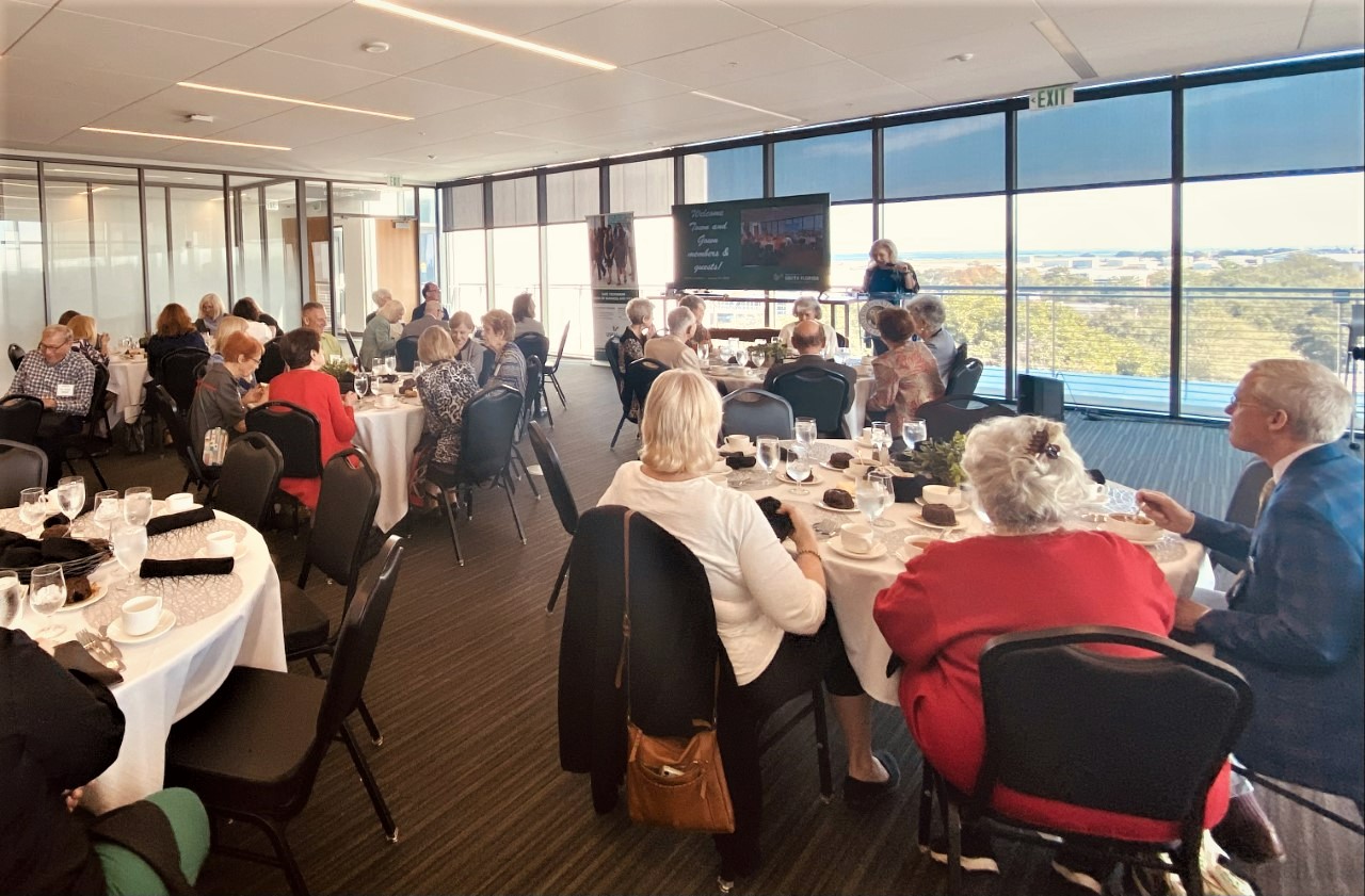 Group of people eating at various tables watching presentation