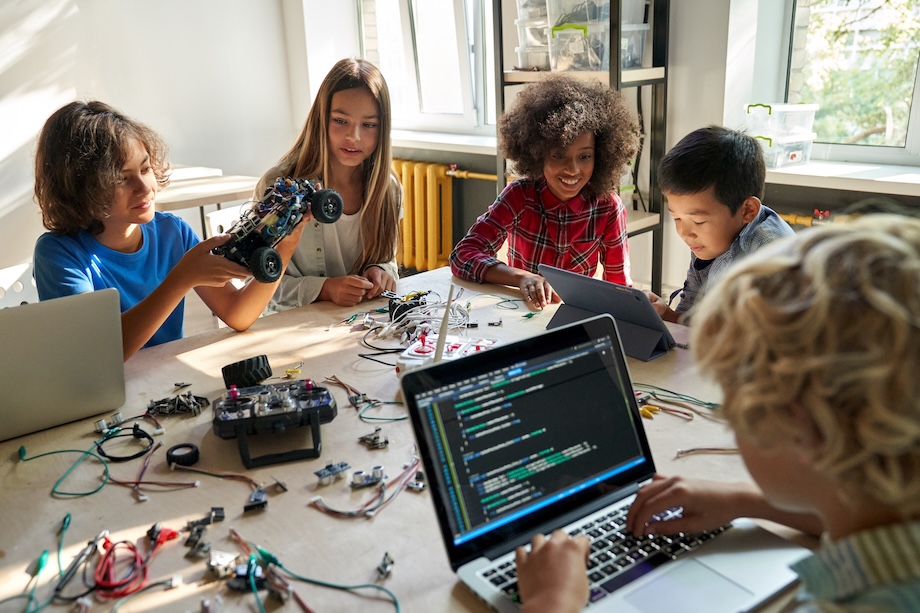 Children working on robotics at a table while one child is working on a laptop