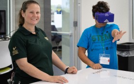 Camp counselor smiling while student wears VR headset 
