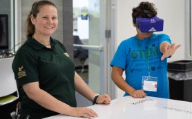 Camp counselor smiling while student wears VR headset