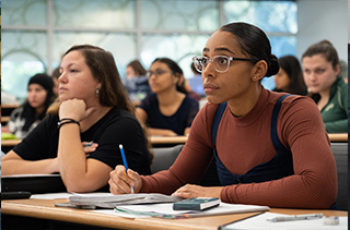 2 serious women listening to lecture and taking notes