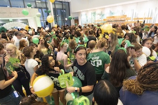 Room full of students wearing green and gold