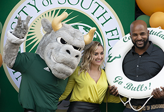 Rocky the Bull with two people posing at graduation