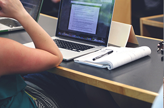 student's arm resting on desk with computer