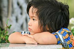 Child leaning on a table with his chin resting on his arms