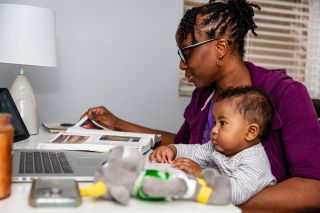 Woman and an infant on her lap looking at laptop screen