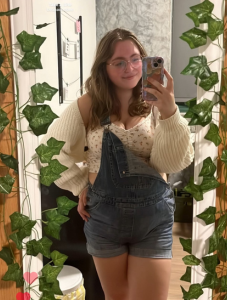Student taking selfie in mirror covered in vines.