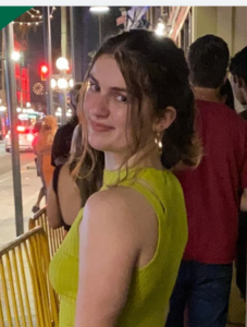 Student wearing green shirt looking over shoulder at camera.