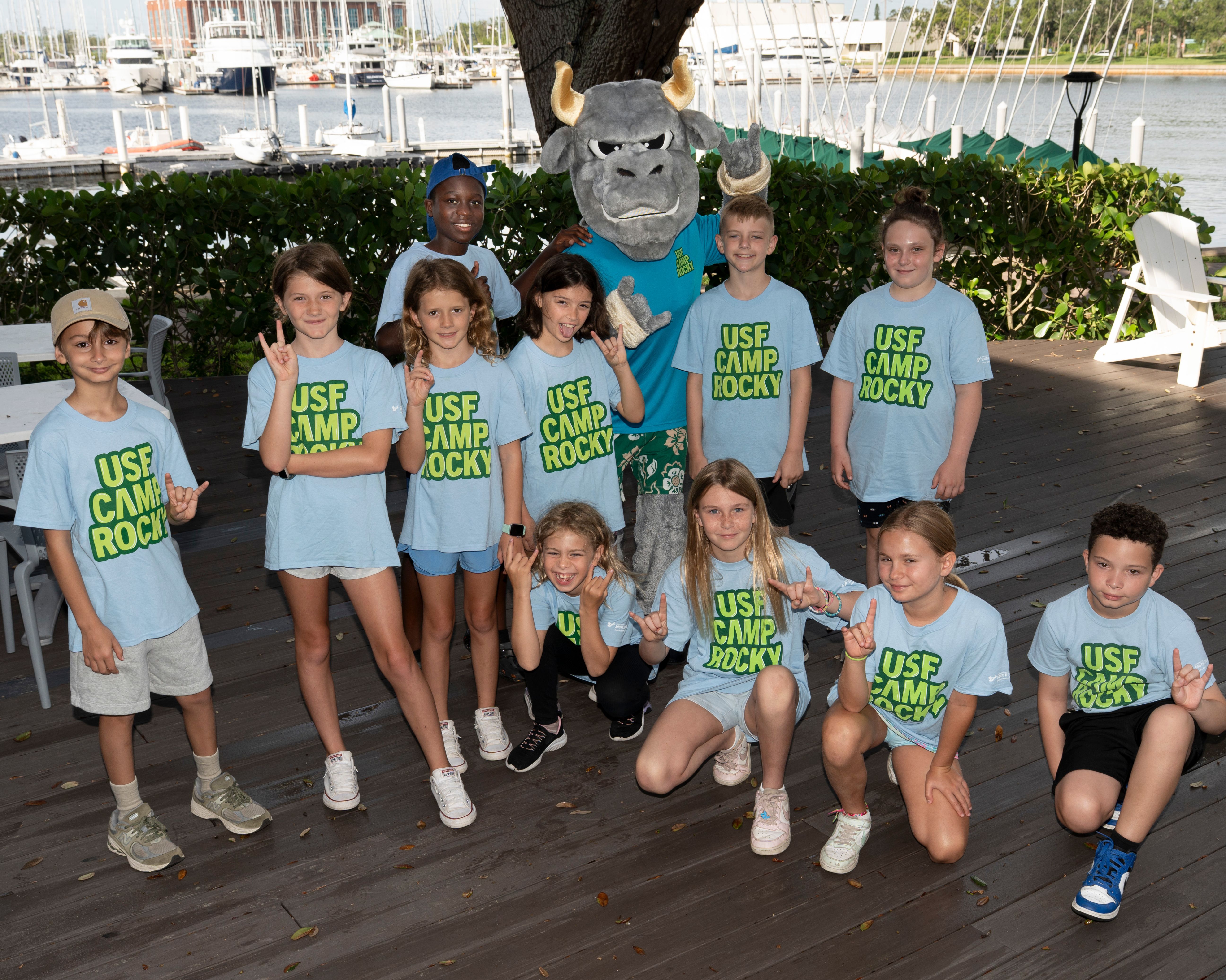 Group of students posing with Rocky the Bull and wearing "USF Camp Rocky" tee shirts