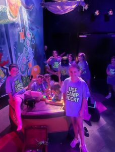 Students playing on play boat smiling and wearing "USF Camp Rocky" tee shirts