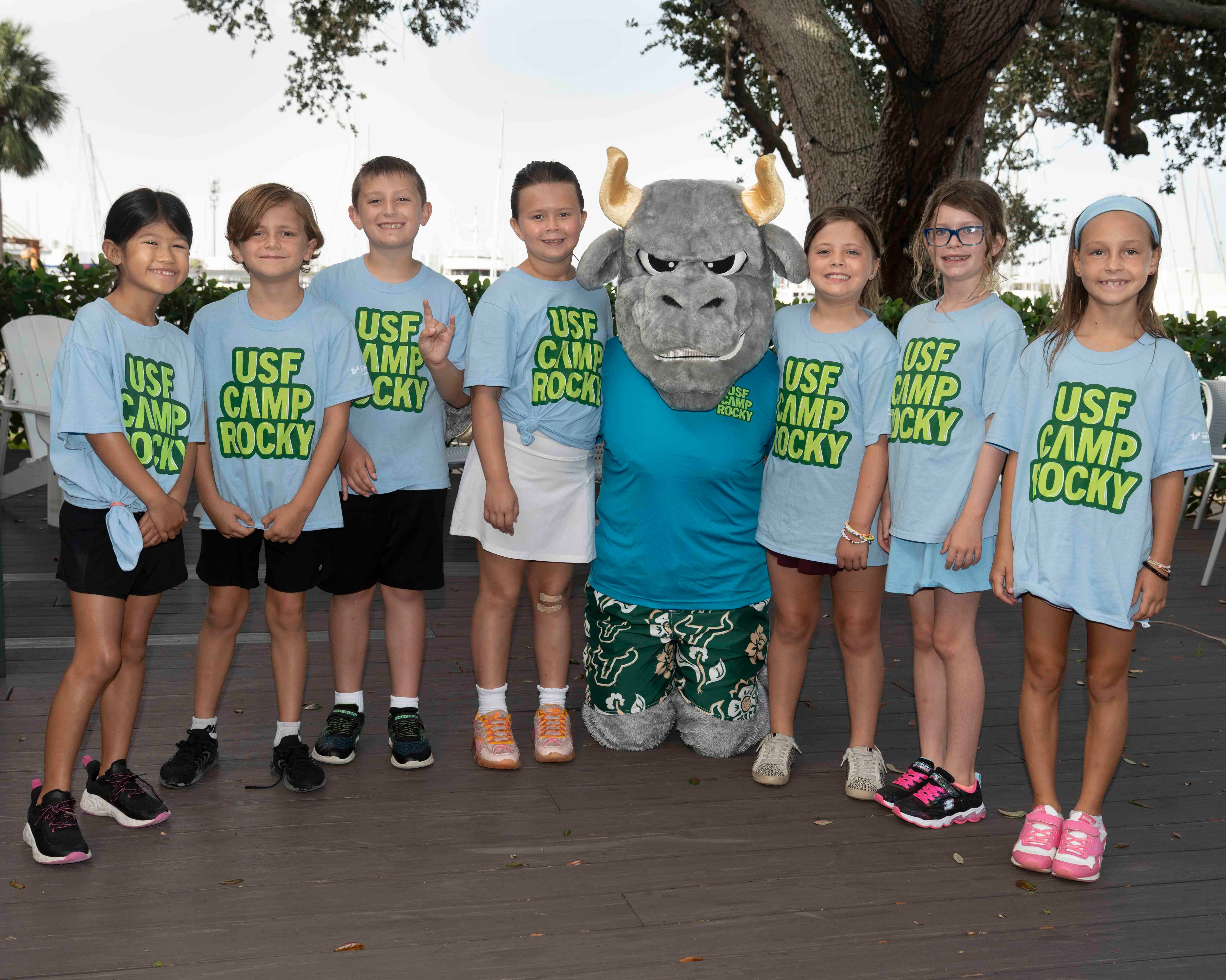 Group of students posing next to Rocky the Bull and wearing "USF Camp Rocky" tee shirts