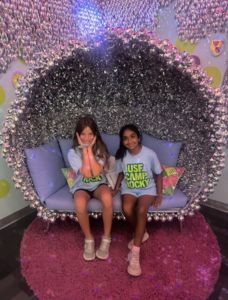 Two students sitting on glittery couch wearing "USF Camp Rock" tee shirts