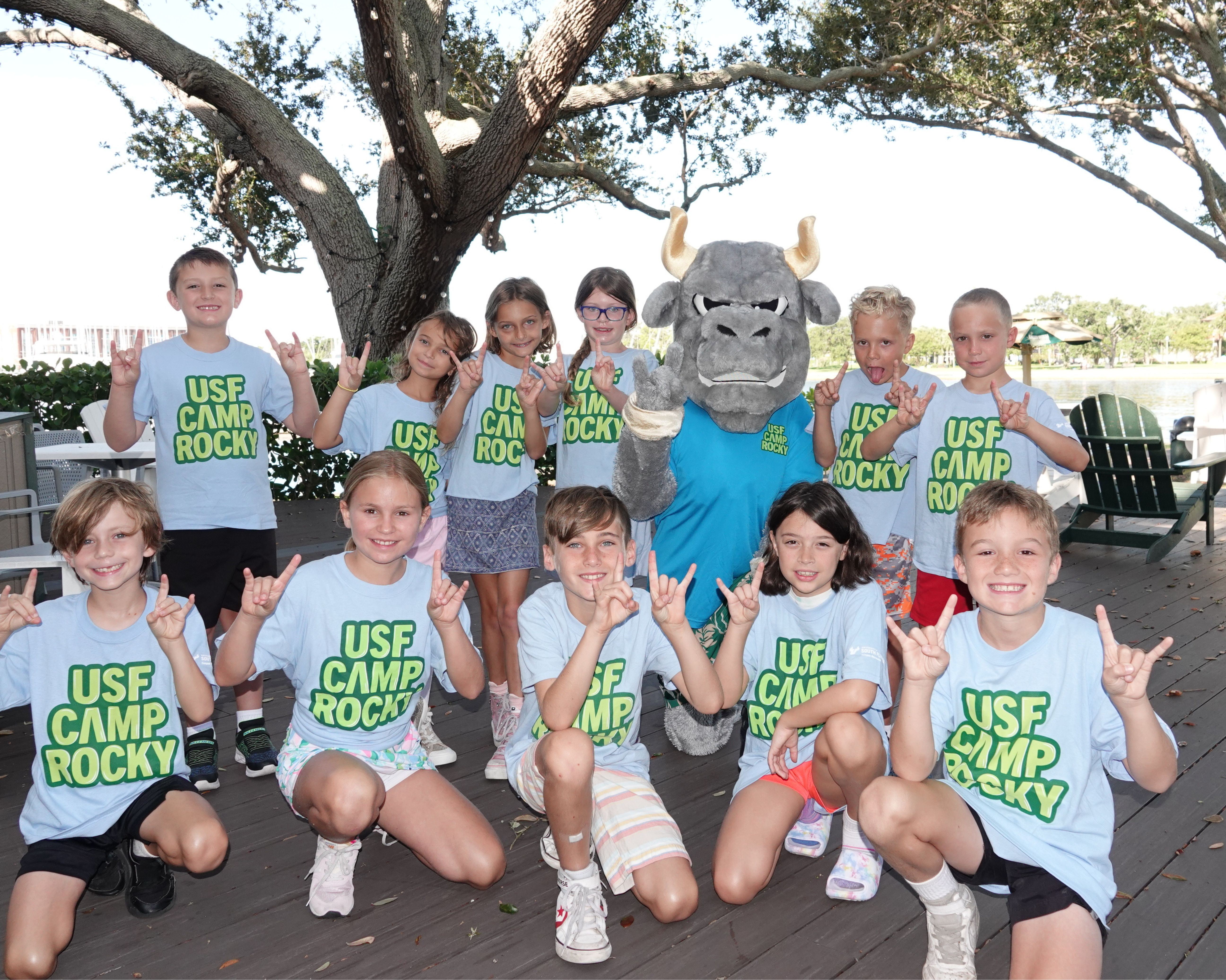 Group of students making Bulls symbol with their hands and wearing "USF Camp Rocky" tee shirts