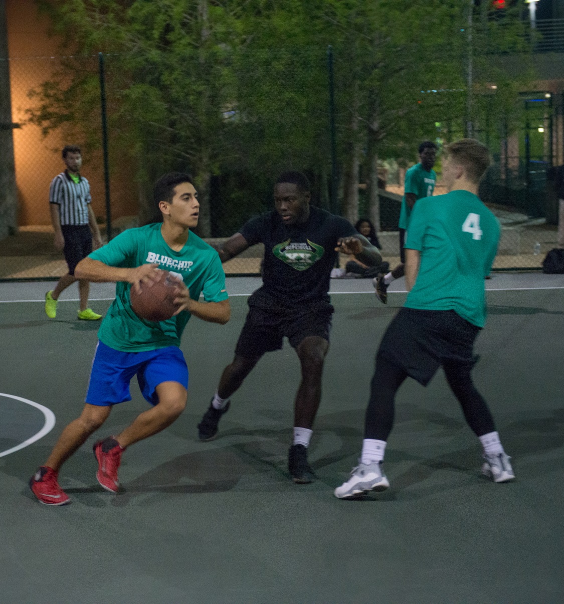 three students playing basketball