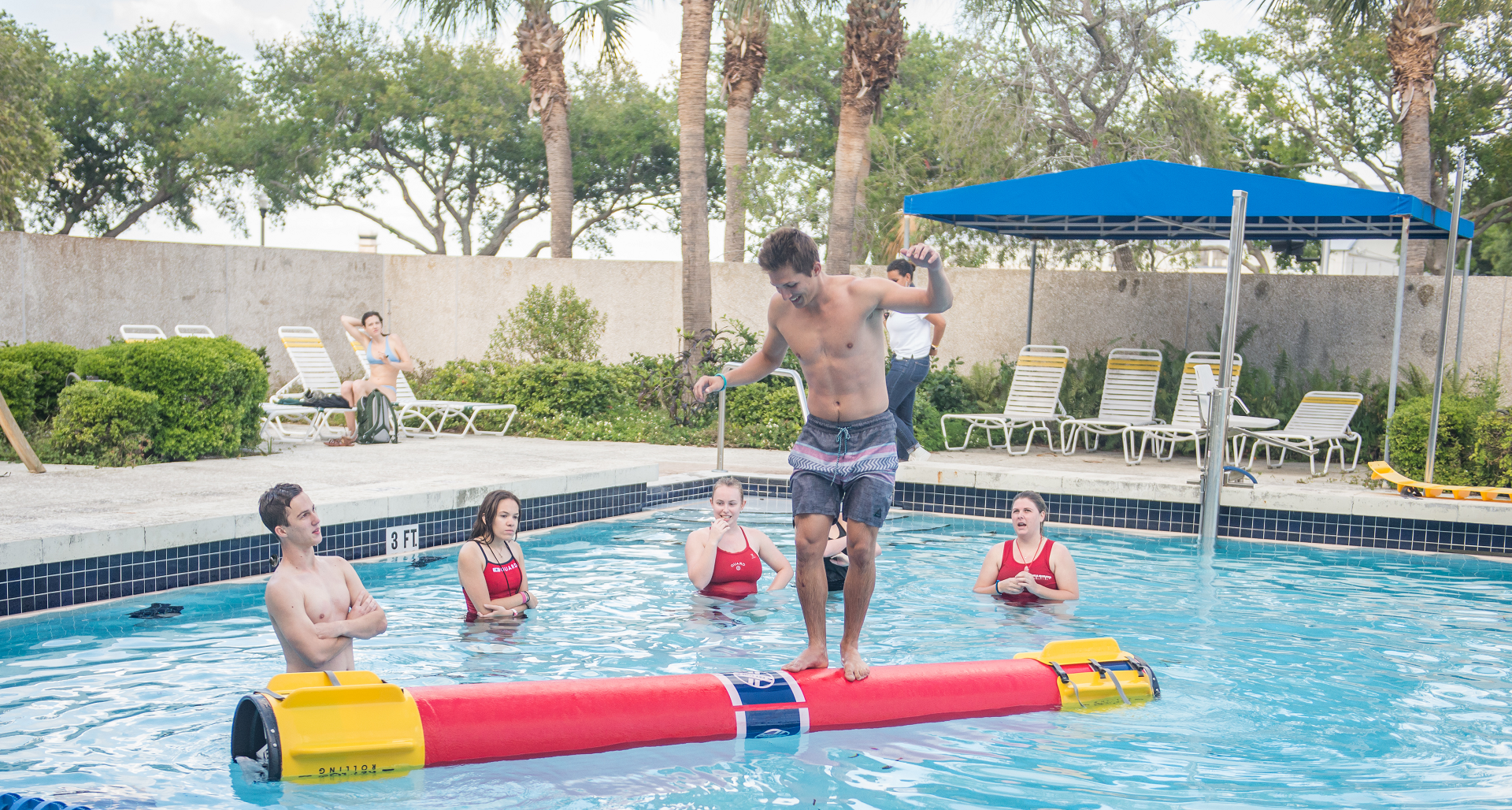 student balances on log roll in pool